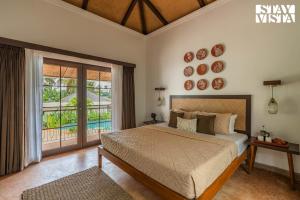 ein Schlafzimmer mit großem Bett und Balkon in der Unterkunft StayVista at Kuhu Natures Resort with BBQ, Pool in Mandrem