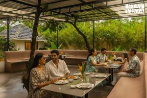eine Gruppe von Menschen, die an Tischen in einem Restaurant sitzen in der Unterkunft StayVista at Kuhu Natures Resort with BBQ, Pool in Mandrem