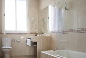 a bathroom with a toilet and a sink and a tub at Hotel Mediodia in Madrid +34 photos