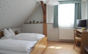 a bedroom with a bed and a desk and a television at Landgasthof Zum Schwarzen Adler in Markt Nordheim