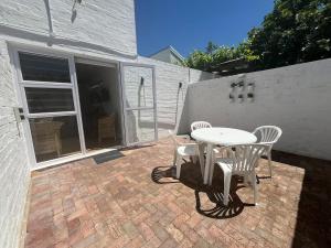 een patio met een tafel en stoelen op een bakstenen patio bij The Sultan Cottage in Stellenbosch