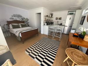 a bedroom with a bed and a kitchen with a table at The Sultan Cottage in Stellenbosch