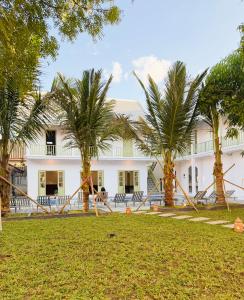 a building with palm trees in front of it at White Elephant Hostel in Luang Prabang