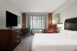 a hotel room with a bed and a desk with a television at Hilton Garden Inn Chicago Downtown/Magnificent Mile in Chicago +50 photos