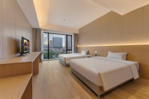 a hotel room with two beds and a television at HeeFun Apartment GZ -Poly World Trading Center in Guangzhou