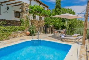 a pool with an umbrella and a table and chairs at Casas Rurales Picachico in Laroya