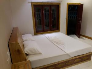 a wooden bed in a room with a window at Zora Beach Inn Mathiveri in Mathiveri