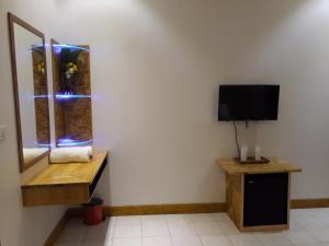 a room with a tv and a bench and a window at Zora Beach Inn Mathiveri in Mathiveri