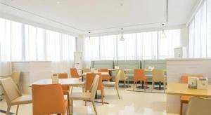 ein Esszimmer mit Tischen und Stühlen und Fenstern in der Unterkunft City Comfort Inn Baise Uprising Memorial Park Laiyu in Qitang