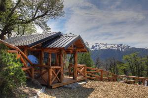 eine Holzhütte mit Bergen im Hintergrund in der Unterkunft Paraiso de Montaña in Villa Pehuenia