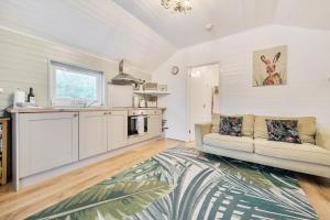 a living room with a couch and a kitchen at Ash Lodge in Ulverston