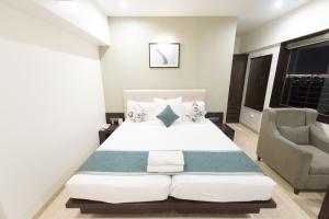 Hotel Le Grande - Mumbai International Airport في مومباي: غرفة نوم بسرير كبير وكرسي