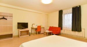 ein Schlafzimmer mit einem Bett und einem Tisch und einem Fernseher in der Unterkunft Jinjiang Inn Qingdao Development Zone Jinggangshan Rd. in Huangdao