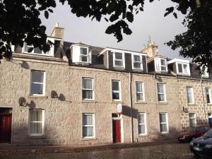 un grand bâtiment en briques avec une porte rouge dans l'établissement Abacus Central Guest House, à Aberdeen