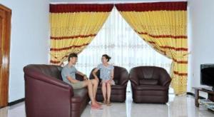 two people sitting on a couch in a living room at Hotel Glee in Challi