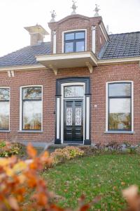 a red brick house with a black door at De Friese Wouden in Suameer