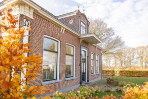 a brick house with a clock on the side of it at De Friese Wouden in Suameer