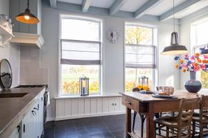 a kitchen with a wooden table and two windows at De Friese Wouden in Suameer +35 photos