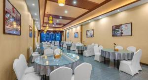 einen Konferenzraum mit Tischen und weißen Stühlen in der Unterkunft GreenTree Inn Kunming Baiyun Road Tongde Plaza Branch in Kunming