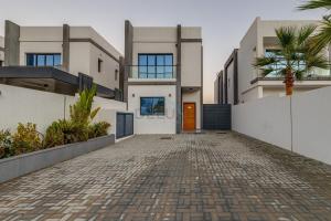 富查伊拉Grand 4BR Villa with Majestic Mountain and Sea Views, Assistant Room, and Private Pool, Just a Few Minutes Drive from Fujairah Finest Beaches and Camping Sites, Al Dana Island, Fujairah by Deluxe Holiday Homes的一栋前面有车道的房子