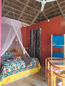 um quarto com uma cama de dossel e uma mesa em Monita Villa Rangiroa em Tiputa