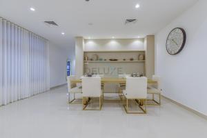 富查伊拉Grand 4BR Villa with Majestic Mountain and Sea Views, Assistant Room, and Private Pool, Just a Few Minutes Drive from Fujairah Finest Beaches and Camping Sites, Al Dana Island, Fujairah by Deluxe Holiday Homes的一间带桌子和白色椅子的餐厅