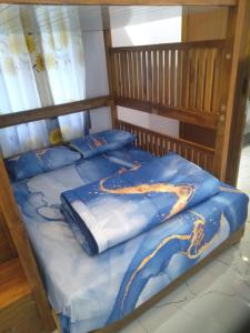 a bed with a blue comforter with a dragon on it at Manggala Homestay Bromo in Ngadisari