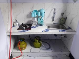 a kitchen counter with a sink and two yellow containers at Manggala Homestay Bromo in Ngadisari