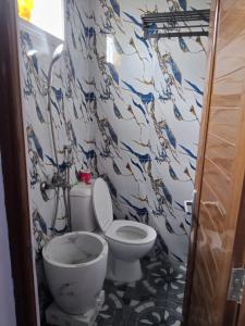 a bathroom with a toilet and a wall withpaintedipes at Manggala Homestay Bromo in Ngadisari