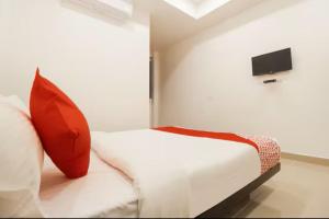 um quarto com uma cama com uma almofada vermelha e uma televisão em Sakthi Grand em Erode