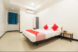 um quarto com uma cama com almofadas vermelhas em Sakthi Grand em Erode