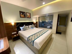 a bedroom with a large bed and a large window at Townhouse Vadodara Railway Junction Formerly Hotel Unique in Vadodara