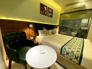 a bedroom with a bed and a chair and a table at Townhouse Vadodara Railway Junction Formerly Hotel Unique in Vadodara