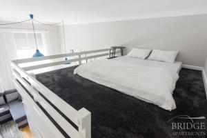 1 dormitorio con cama blanca y alfombra negra en Bridge Apartments, en Cracovia