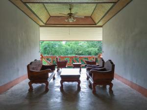 un soggiorno con sedie, tavolo e ampia finestra di Baan Khue Wieng Resort a Mae Sariang
