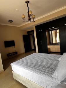 ein Schlafzimmer mit einem großen weißen Bett mit einem Kronleuchter in der Unterkunft Urban 2 Bedroom Serviced Apartment in Nakasero in Nalakonge + 14 Fotos