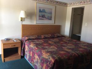 a hotel room with a bed and a night stand at West Motel in Freeport
