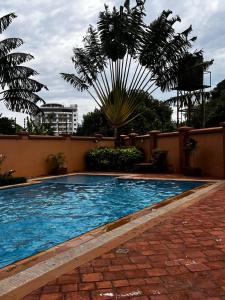 einen Pool mit einer Palme neben einem Gebäude in der Unterkunft Urban 2 Bedroom Serviced Apartment in Nakasero in Nalakonge
