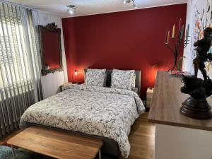 a bedroom with a bed and a red wall at Domus26 Chambre ORIENTEM in Montaigu-Vendée