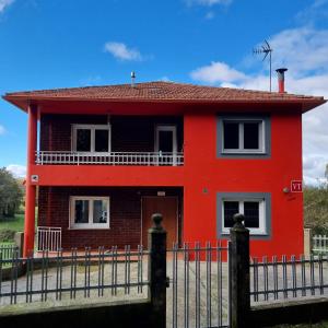 ein rotes Haus mit einem Zaun davor in der Unterkunft As Neveiras in Millerada