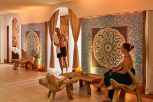 a man and a woman sitting in a room with a table at Sofitel Golfe d'Ajaccio Thalassa Sea & Spa in Ajaccio