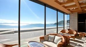 a room with chairs and tables and a view of the ocean at Shinojima Royal Hotel Kasuisou in Minamichita