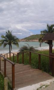 a wooden boardwalk leading to the beach at Pousada Enseada do Coqueiro in Guarapari