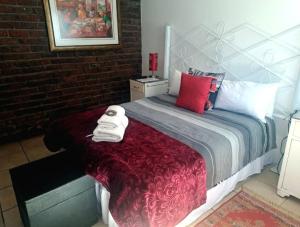 ein Schlafzimmer mit einem Bett mit roten und weißen Kissen in der Unterkunft Sundown Lodge and Confrence in Aliwal North