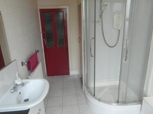 a bathroom with a shower and a sink and a red door at Abacus Central Guest House in Aberdeen
