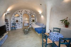 a bedroom with a bed and a table and chairs at Αura Cave in Fira