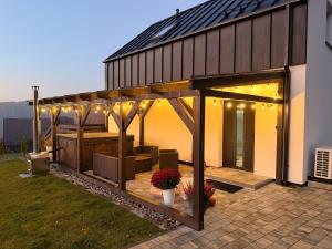 a house with a pergola on a patio at KASZUBY - Domki na Szczycie - jeden na ogrodzonej działce z balia jacuzzi na wyłączność in Krzeszna