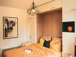 a bedroom with a bed with orange sheets and pillows at Le Retro Gaming - Le Havre Train Station in Le Havre