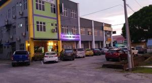 ein Parkplatz mit vor einem Gebäude geparkten Autos in der Unterkunft HOTEL BAJET MUGHOH SENGOTI in Kampong Gong Kempas