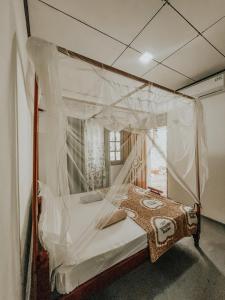 1 dormitorio con cama con dosel cubierta de plástico en Hiriketiya Lima Homestay, en Dikwella